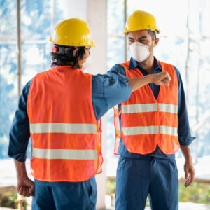 colleagues-with-safety-equipment-working-with-blueprints